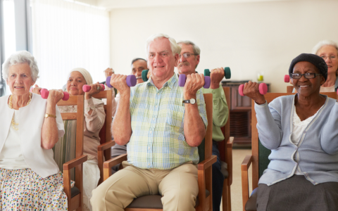 older people sit in chairs and lift weights