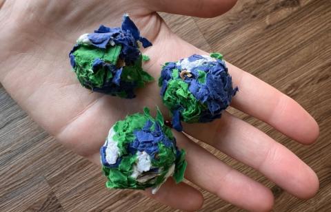 Three seed bombs are held in a human hand.