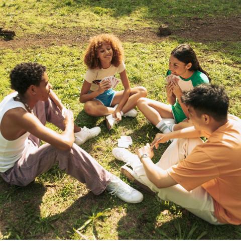 Teens gathered around sitting in the grass